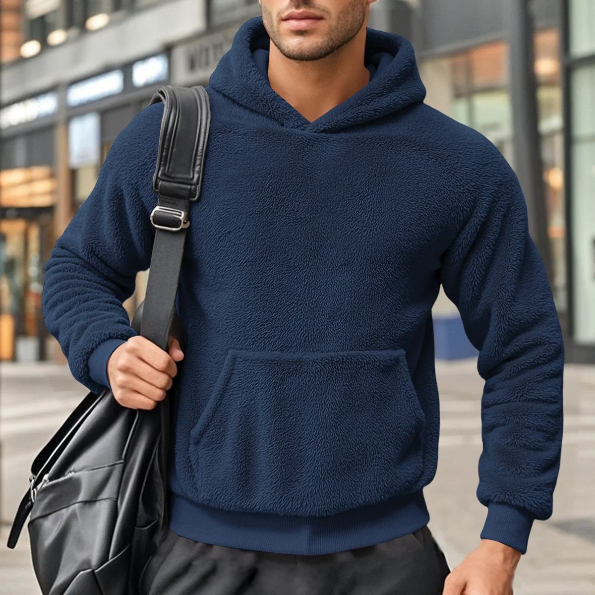 Navy blue teddy fleece hoodie worn by a male model, shown from the front with a shoulder bag.