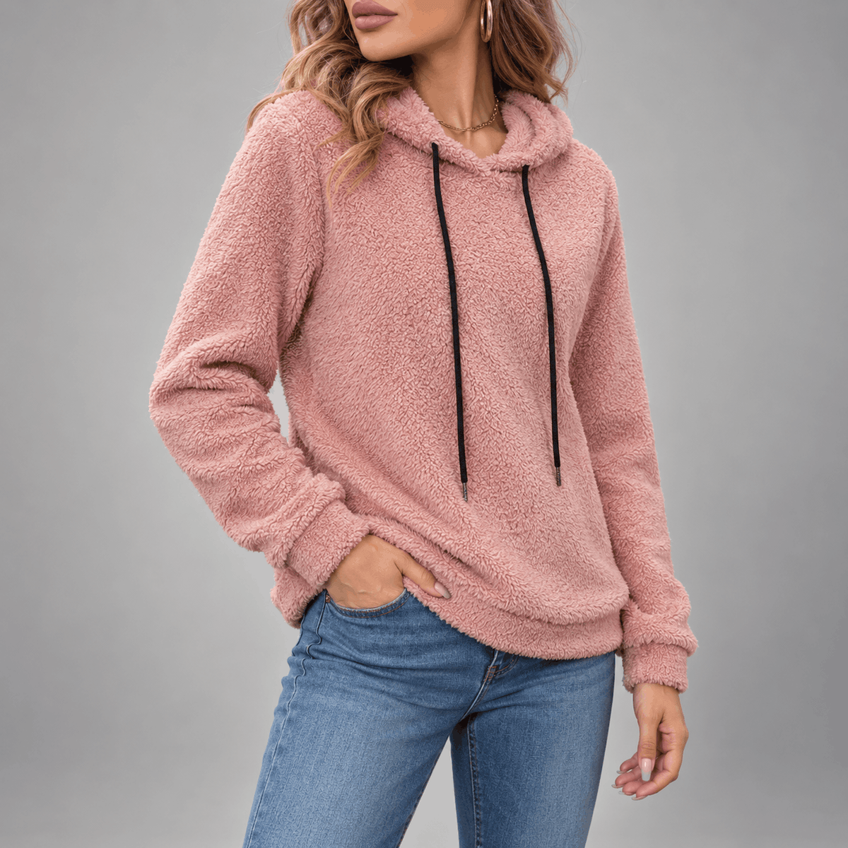 Teddy Fleece Pullover Hoodie – Pink hoodie worn by a female model in a front-facing stance with hands in the kangaroo pocket