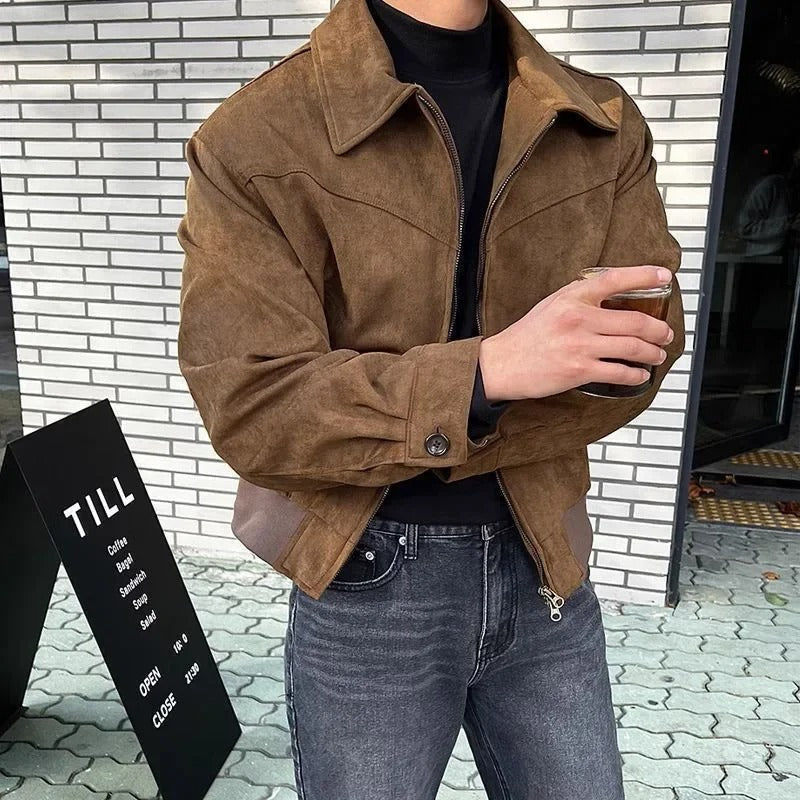 Brown suede bomber jacket with a point collar, zip-front closure, and buttoned cuffs worn over a black turtleneck.
