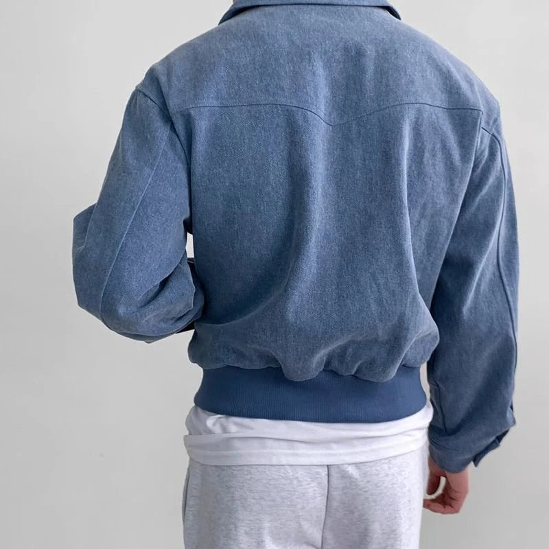 Blue suede bomber jacket with a point collar, elasticized hem, and tailored fit viewed from the back.