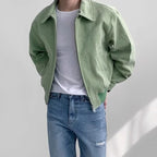 Sage green suede bomber jacket with a point collar, zip-front closure, and elasticized hem worn over a white tee.