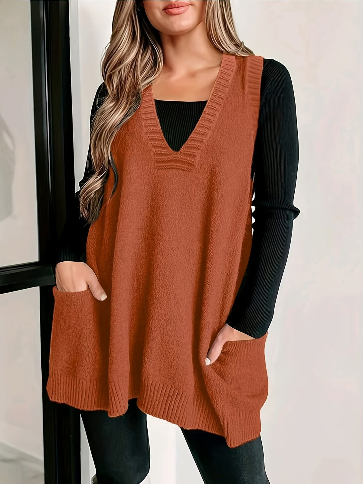 Front view of a model wearing the rust orange fuzzy knit V-neck sweater vest with front patch pockets over a black long-sleeve shirt.
