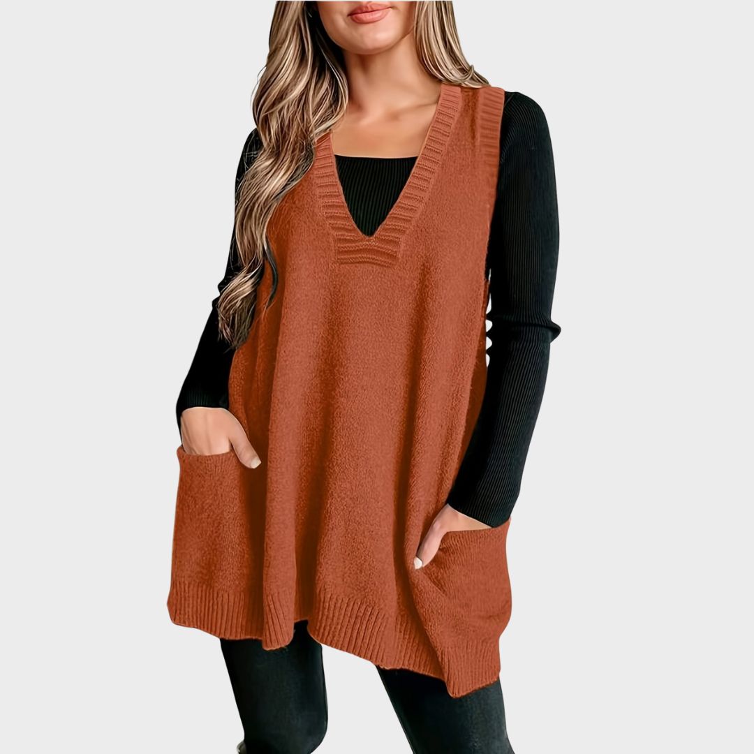 Front view of a model with hands in pockets wearing a rust orange fuzzy knit V-neck sweater vest featuring ribbed neck trim and deep front patch pockets, layered over a long-sleeve black top.