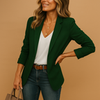 Tailored forest green blazer with notched lapels, structured shoulders, and long sleeves worn over a white v-neck top.
