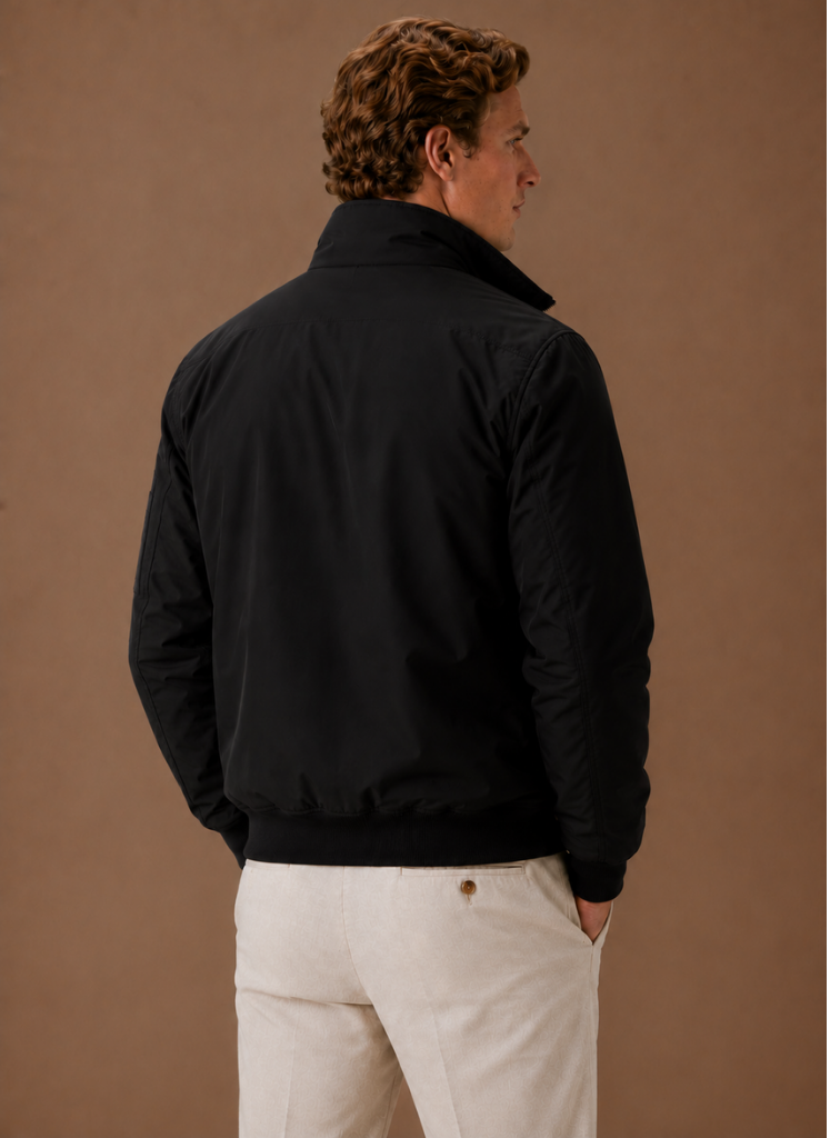 Back view of a man wearing a black utility bomber jacket with a stand collar and streamlined silhouette.