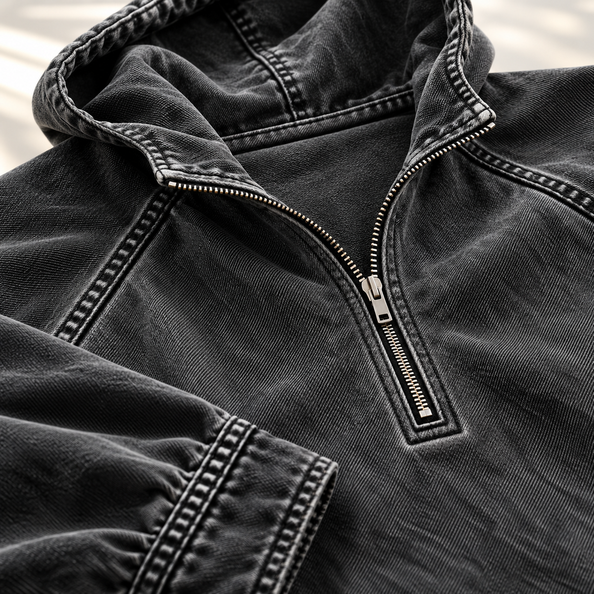 Close-up of the black hoodie showing the half-zip collar and contrast topstitching.