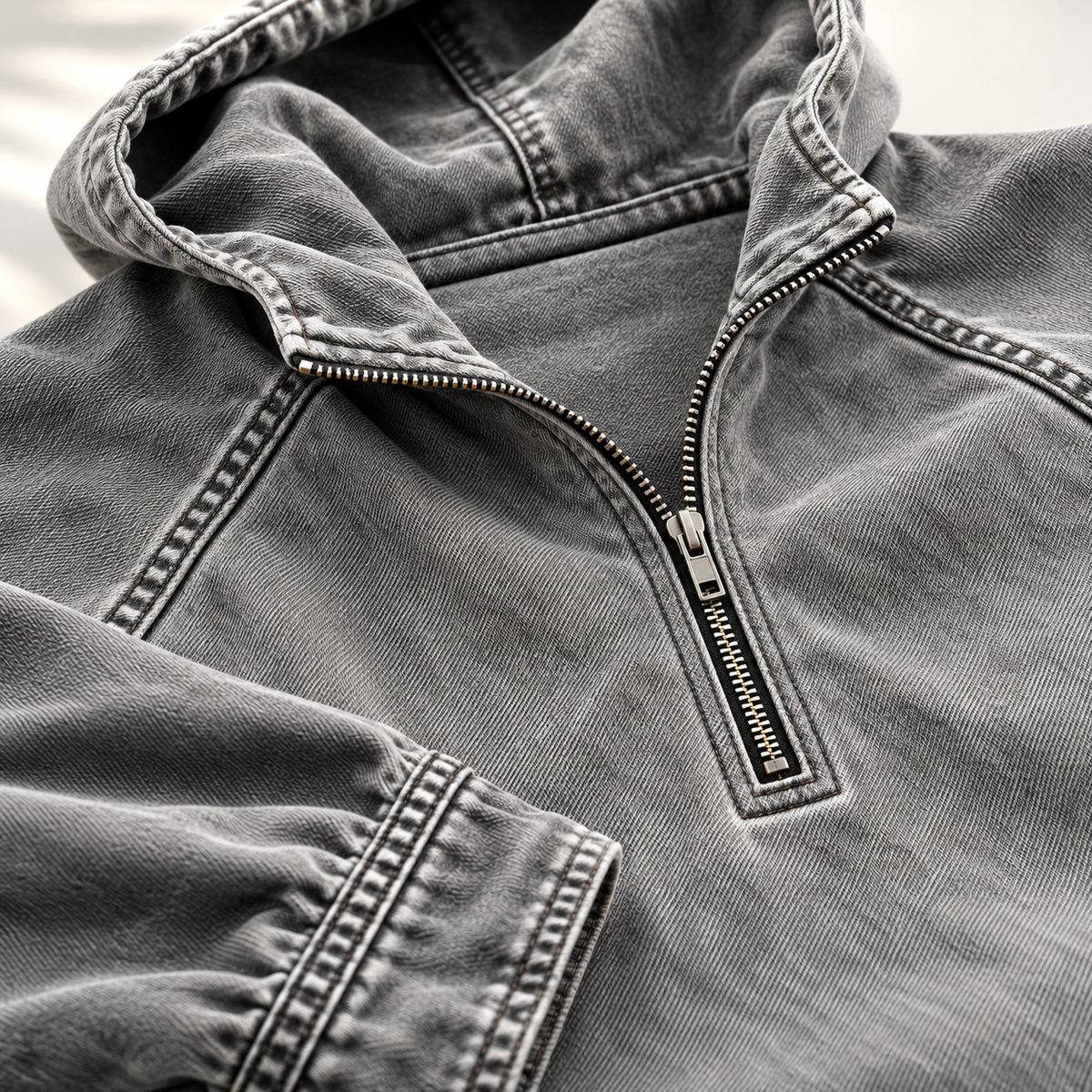Close-up of the gray hoodie showing the half-zip collar, raglan seam, and contrast topstitching.