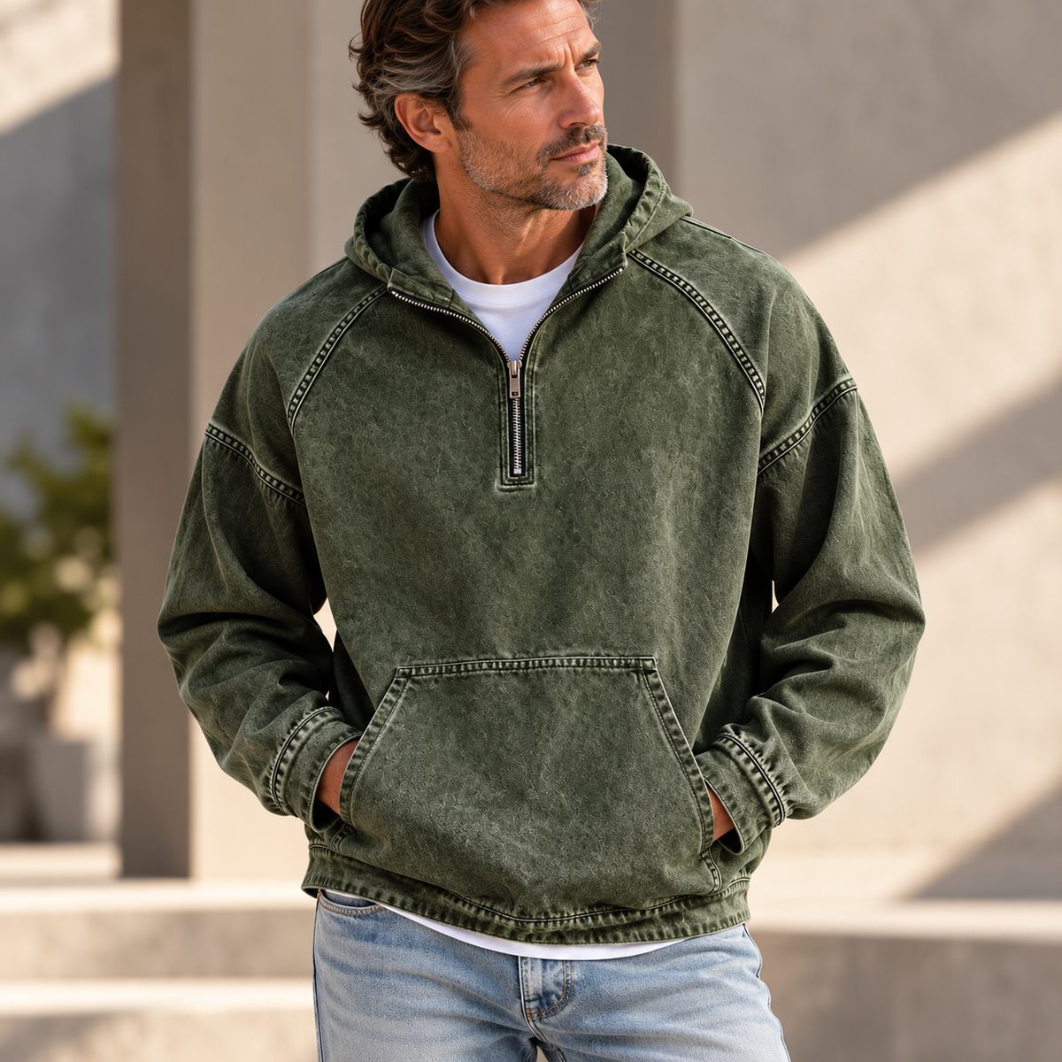 Green washed half-zip hoodie worn by a male model, featuring raglan sleeves and a kangaroo pocket.