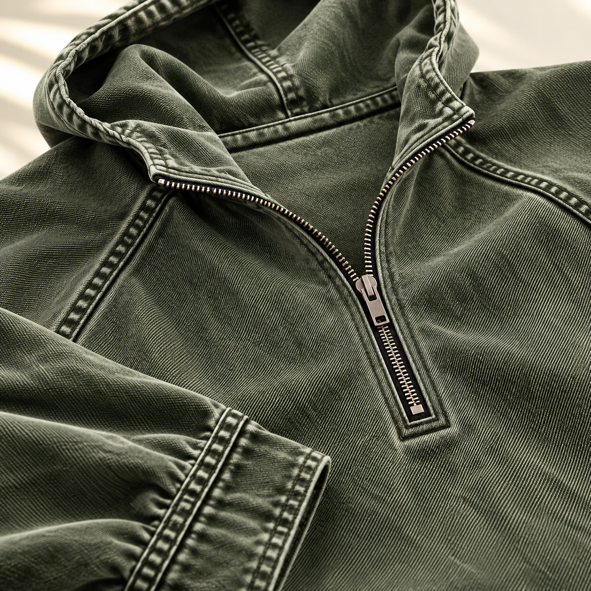 Close-up of the green hoodie showing the half-zip collar and contrast topstitching.