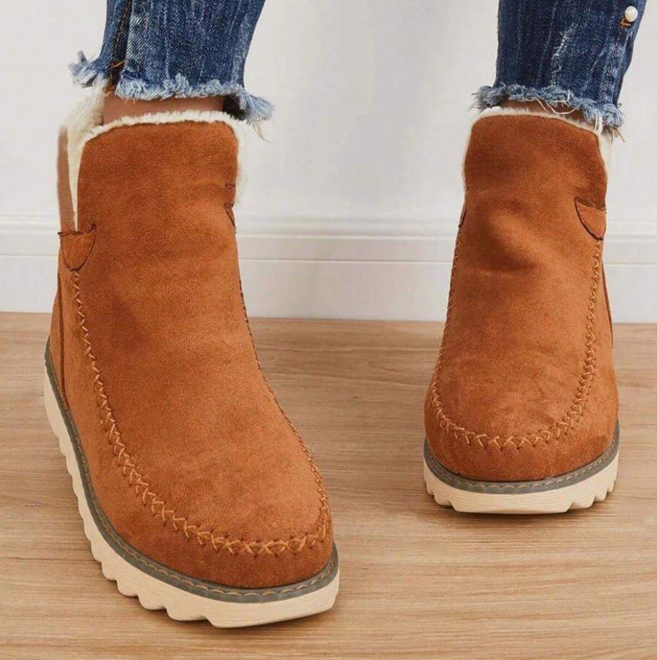 Brown suede moc toe ankle boots for women worn with cropped jeans on a wooden floor