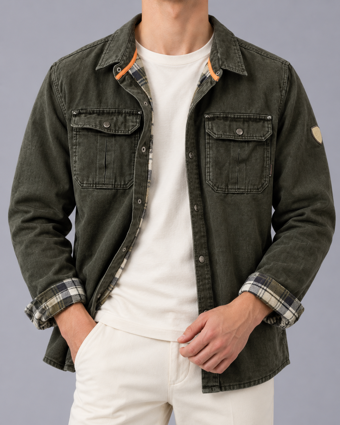 Front view of a model wearing the waxed cotton jacket in dark olive green featuring snap front closure, dual chest pockets, and plaid lining details at the collar and cuffs.