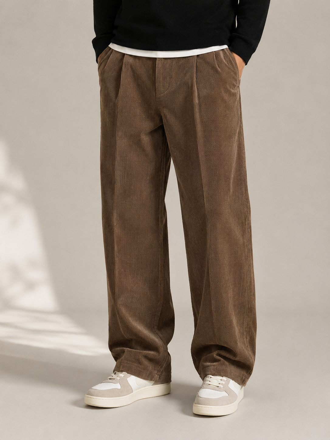 Brown wide-leg corduroy trousers with double front pleats, a sharp center crease, and a relaxed, straight-leg silhouette.