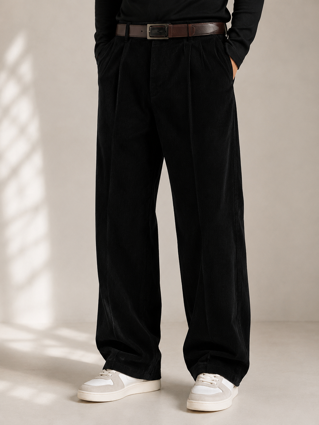 Black wide-leg corduroy trousers featuring double front pleats, a pressed center crease, and a relaxed straight-leg fit.