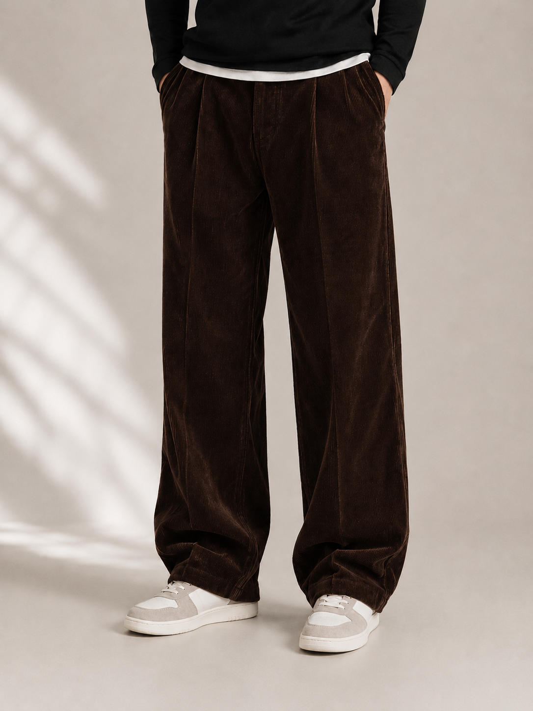 Dark brown wide-leg corduroy trousers with double front pleats, a sharp center crease, and a relaxed, straight-leg fit.