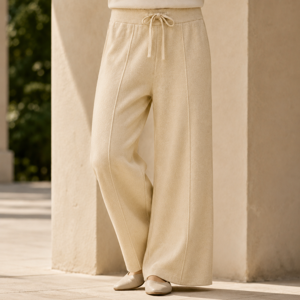 Beige wide-leg merino wool knit pants featuring a ribbed drawstring waist and full-length relaxed silhouette.