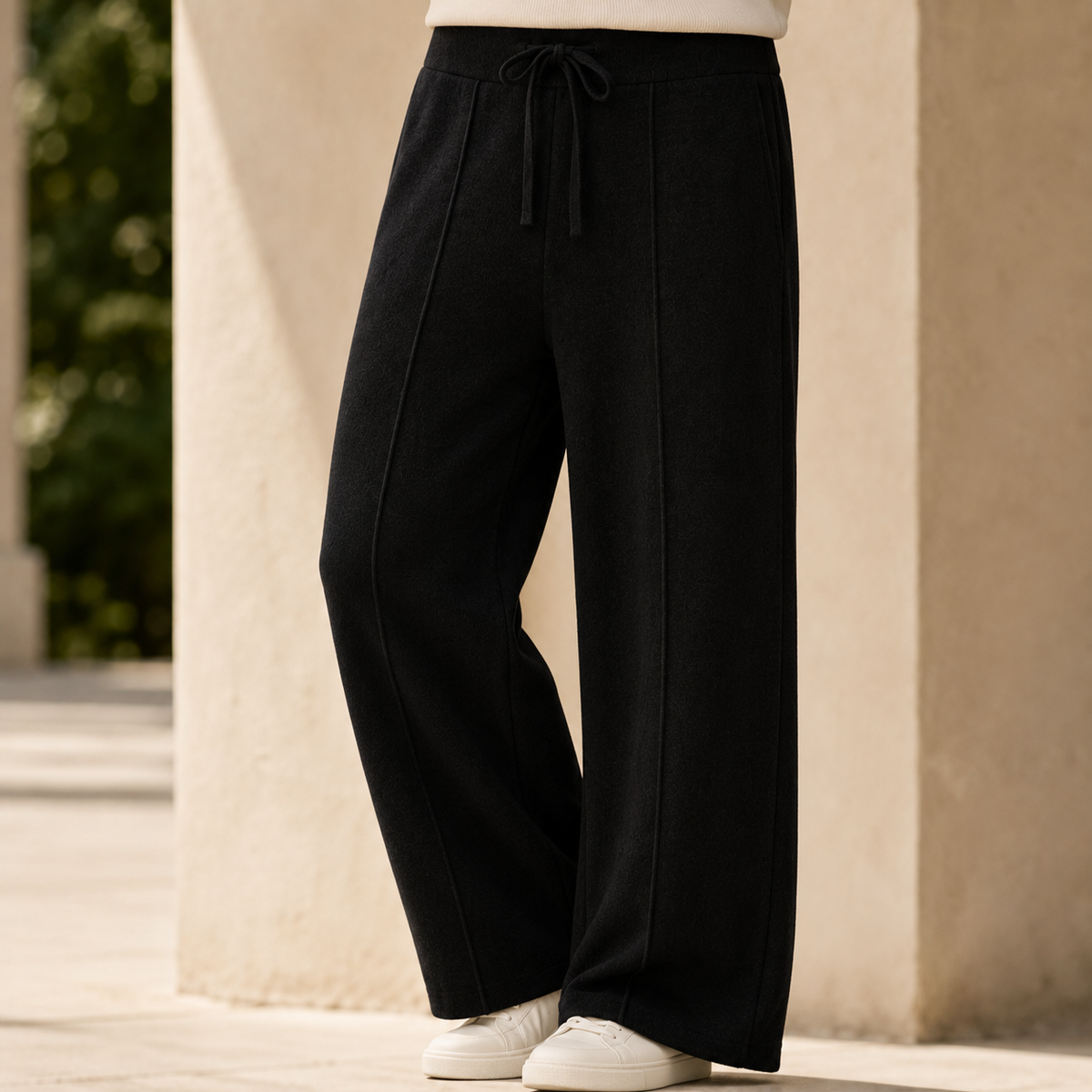 Black wide-leg merino wool pants featuring a ribbed drawstring waist and center-seam detailing in a relaxed knit fit.