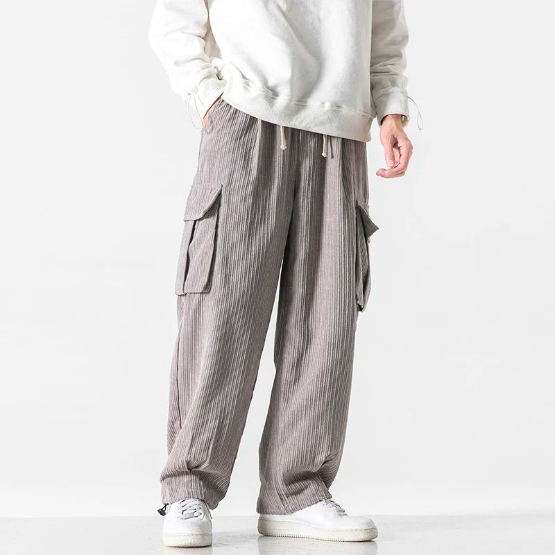 Gray corduroy cargo pants shown from the side with wide legs and drawstring waist