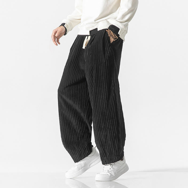 Black wide-wale corduroy harem pants with a drawstring waist, relaxed fit, and tapered gathered ankles.