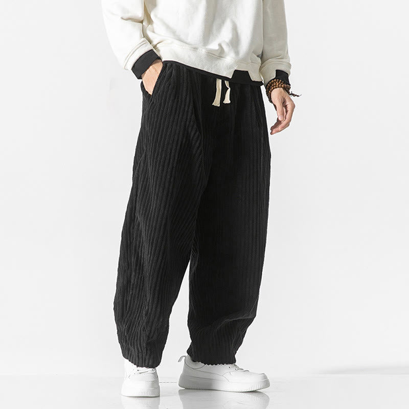 Black wide-wale corduroy harem pants featuring a drawstring waist, roomy seat, and tapered ankles with side pockets.