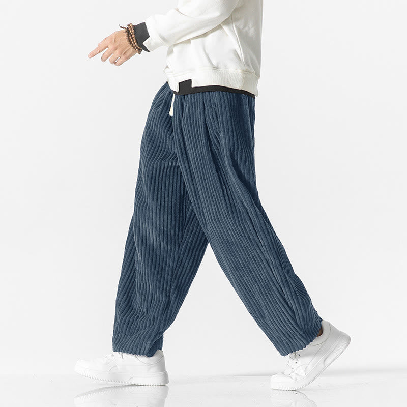 Blue wide-wale corduroy harem pants with a drawstring waist, relaxed fit, and tapered ankle worn with white sneakers.