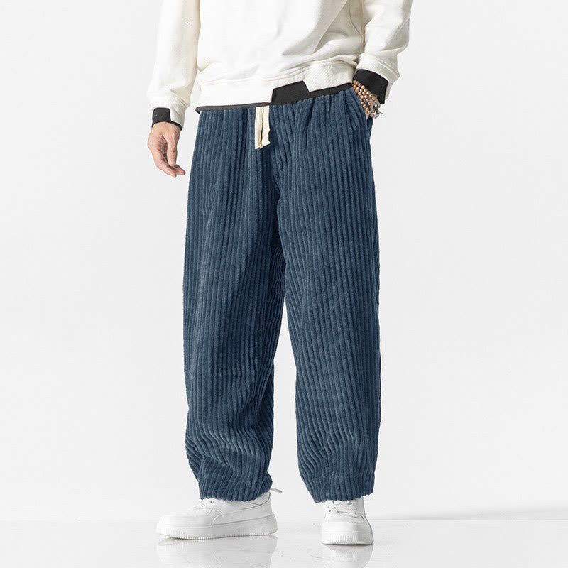 Blue wide-wale corduroy harem pants with a drawstring waist, roomy fit, and tapered ankles worn with white sneakers.