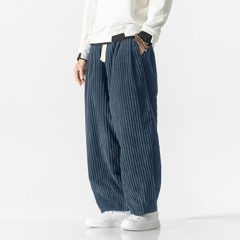 Blue wide-wale corduroy harem pants with a drawstring waist, relaxed fit, and tapered ankle worn with white sneakers.