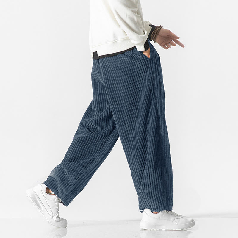 Blue wide-wale corduroy harem pants with a drawstring waist, roomy fit, and tapered ankles paired with white sneakers.