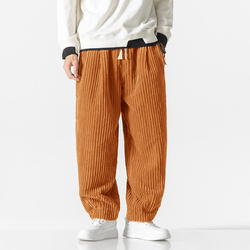 Orange wide-wale corduroy harem pants featuring a drawstring waist, relaxed fit, and tapered ankles with white sneakers.