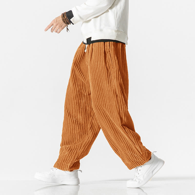Orange wide-wale corduroy harem pants with a drawstring waist, relaxed fit, and tapered ankles worn with white sneakers.