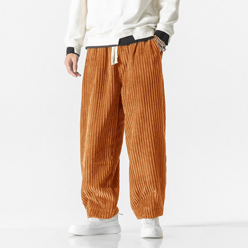 Orange wide-wale corduroy harem pants featuring a drawstring waist, roomy fit, and tapered ankles over white sneakers.