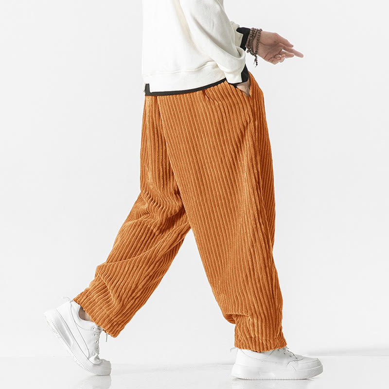 Orange wide-wale corduroy harem pants featuring a relaxed fit, drawstring waist, and tapered ankles worn with white sneakers.