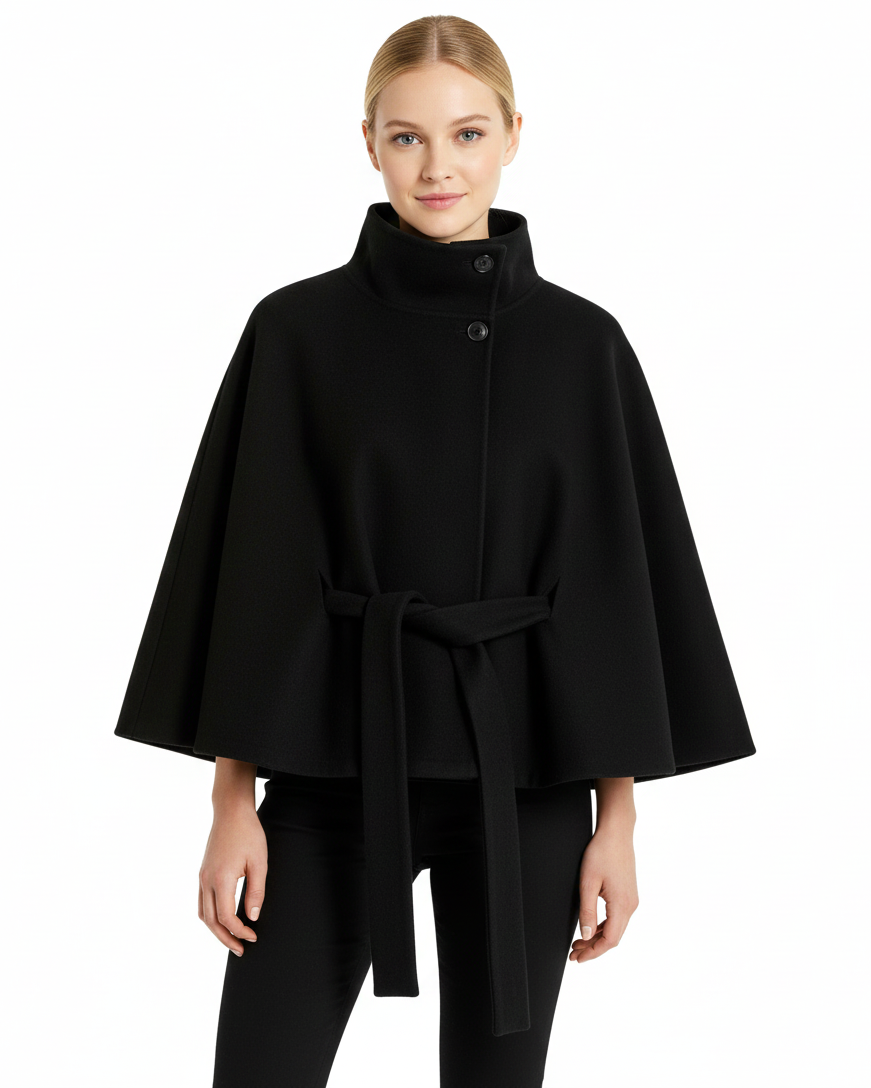 Front view of a model wearing a black belted wool cape coat with a high stand collar, wide sleeves, and matching tie belt, paired with black pants.