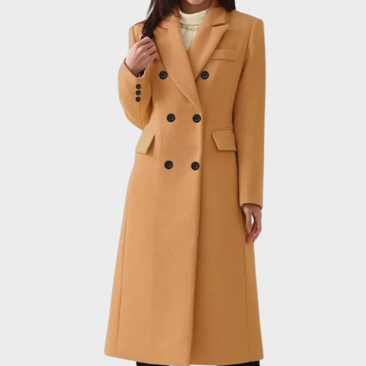 Front view of a woman wearing a camel tan longline double-breasted wool-blend coat with sharp notch lapels, dark contrasting buttons, flap waist pockets, a welt chest pocket, and three-button sleeve cuffs, layered over a white top. 
