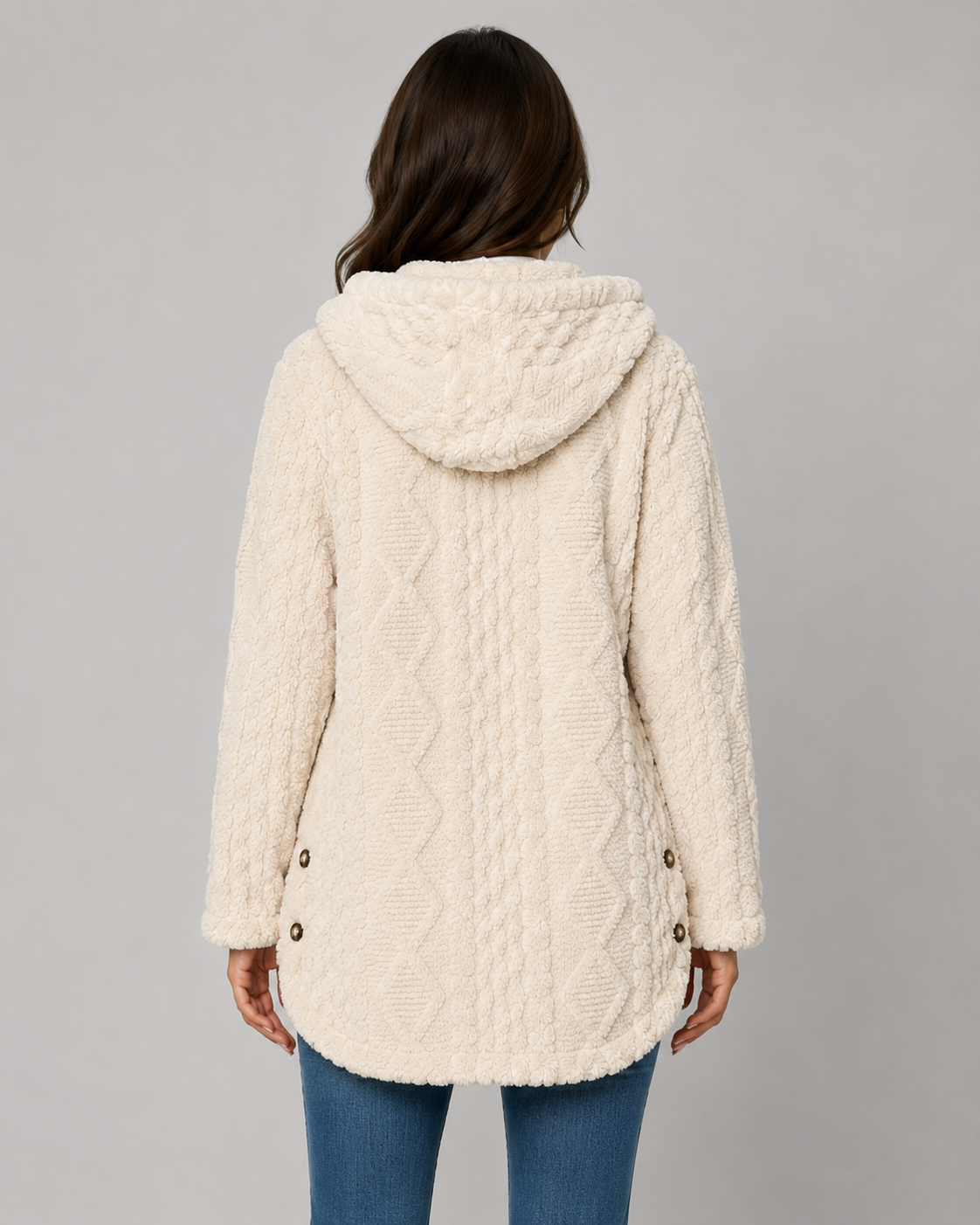Back view of a woman wearing a cream cable-knit textured longline teddy fleece jacket with a hood, curved hem, and side-slit buttons.