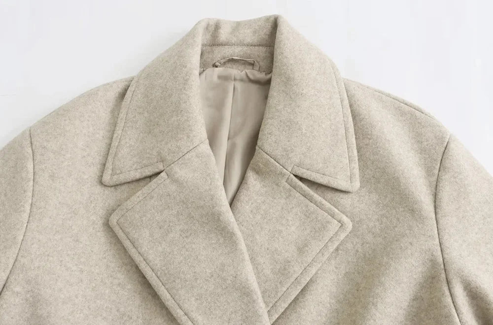 Close-up view of the structured notch lapels, collar, and neck seam detail of the light beige wool coat.