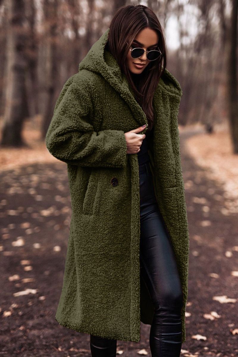 A woman wearing a longline olive green hooded teddy coat with button detail, styled outdoors over black trousers and sunglasses.
