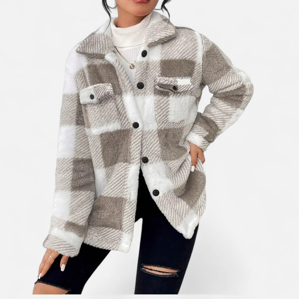 A woman wearing a gray-and-beige plaid plush teddy fleece shacket over a white turtleneck and black ripped jeans.