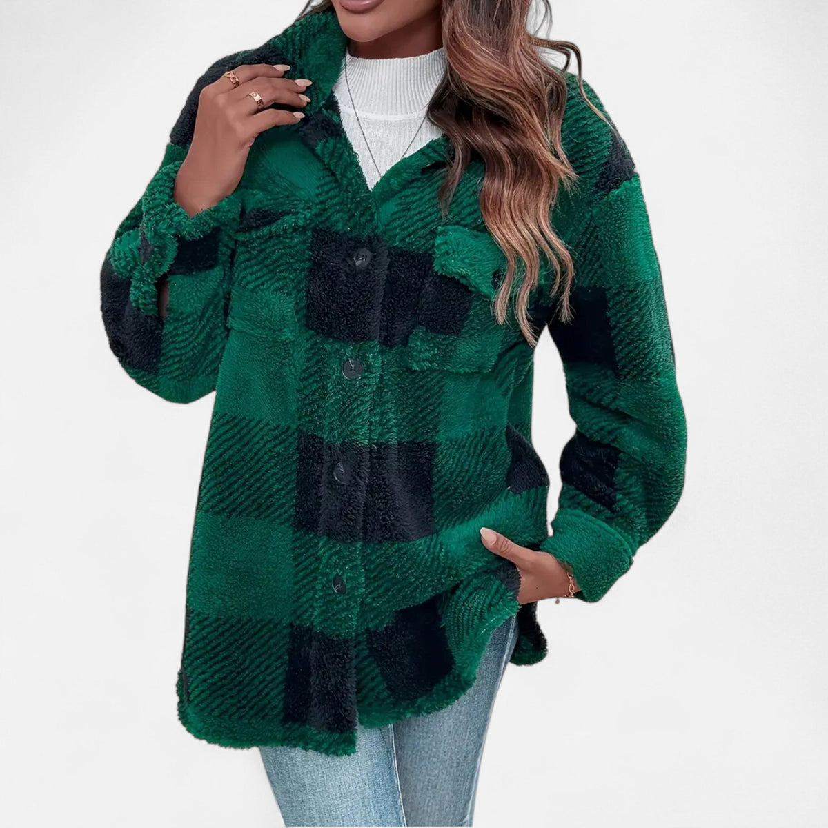 A woman wearing a dark green-and-black plaid plush teddy fleece jacket styled over a white top and blue jeans.