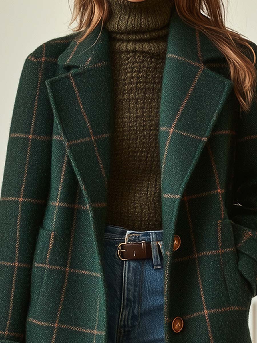 Close-up shot of the notch lapel collar and chest section of the dark green plaid tweed coat, layered over a textured olive green knit turtleneck sweater.