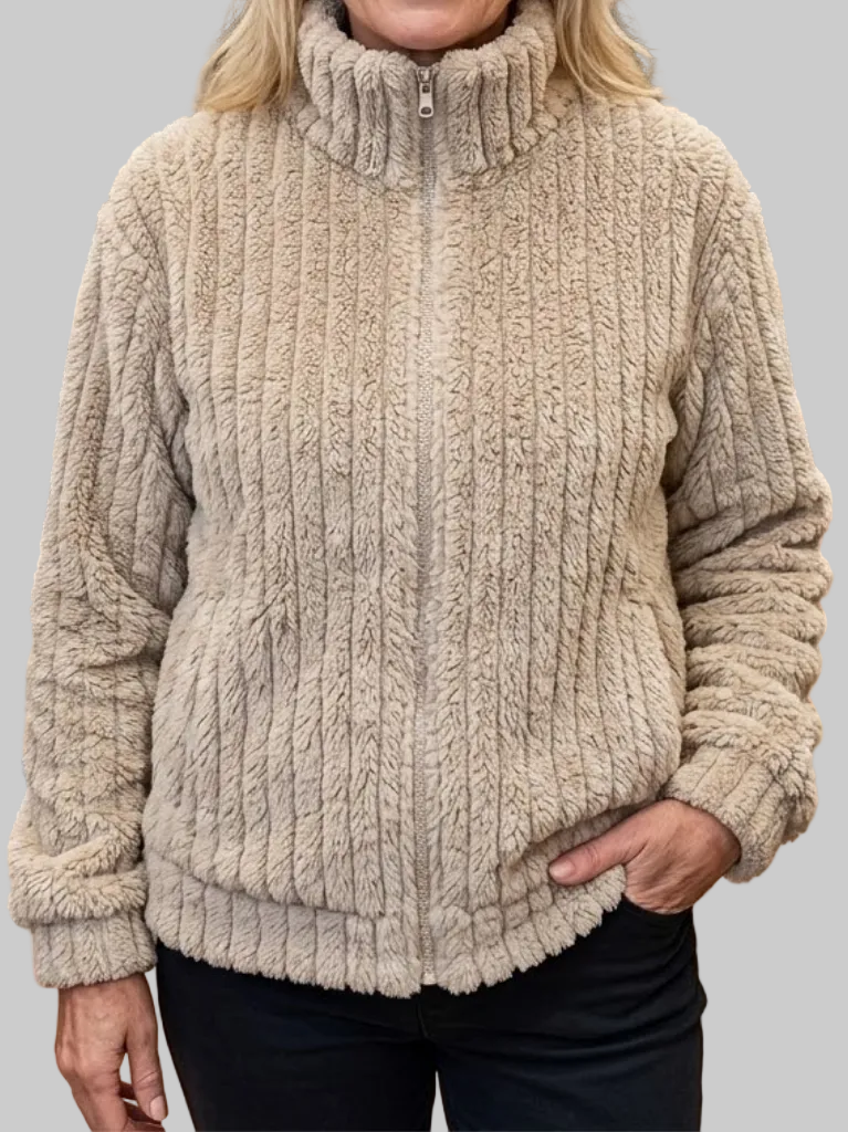 Front view of a woman wearing a beige-tan ribbed fleece zip-up jacket with a zipped high stand collar, long sleeves, and side pockets, styled with dark pants.