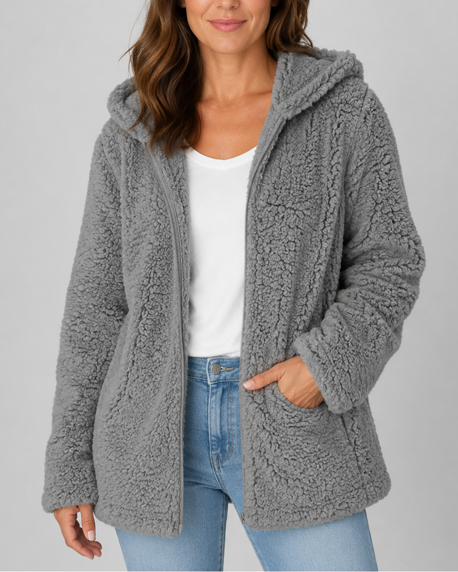 A woman wearing a charcoal gray hooded teddy fleece jacket worn open over a white v-neck tee and blue jeans.