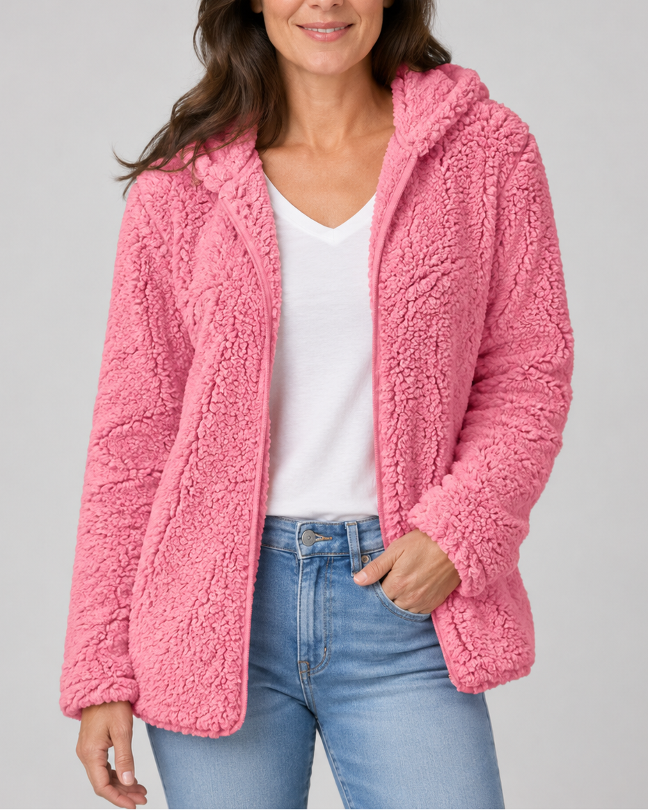 A woman wearing a bright fuchsia pink hooded teddy fleece jacket open over a white v-neck shirt and light jeans.