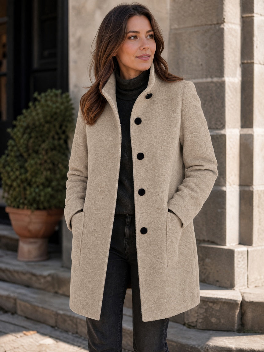 Three-quarter street style portrait of a model wearing the women's wool coat in off-white cream featuring black contrast buttons and patch pockets.