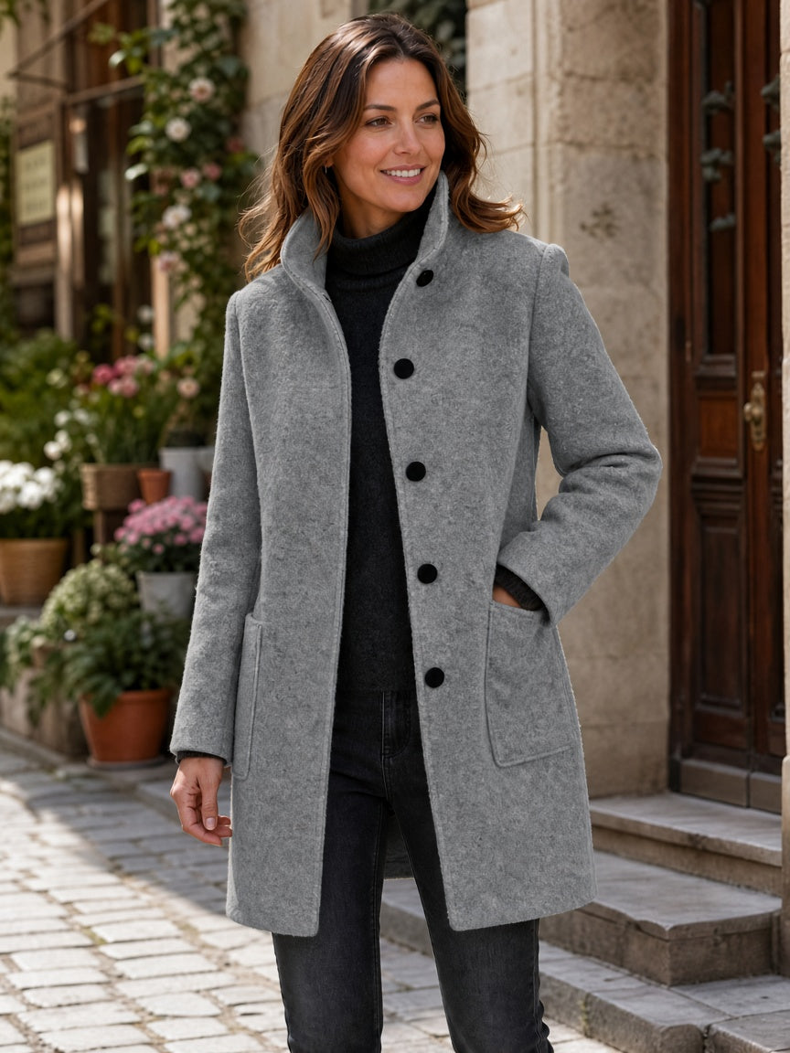 Gray wool-blend coat worn by a woman, featuring a button front, stand collar and patch pockets