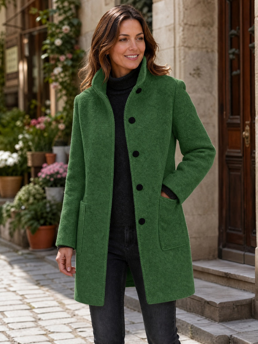 Green wool-blend coat worn by a woman, featuring a stand collar and button closure