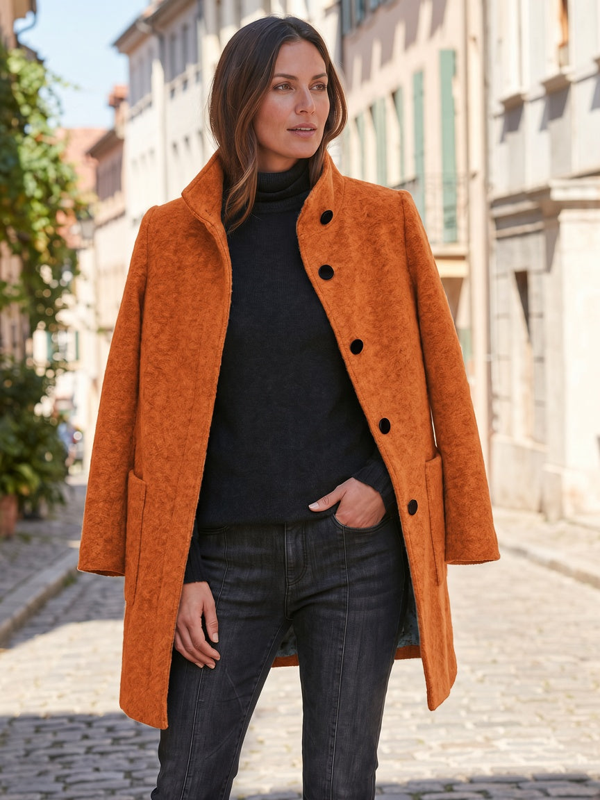 Orange women's coat styled with a black outfit, showing the straight silhouette and long sleeves