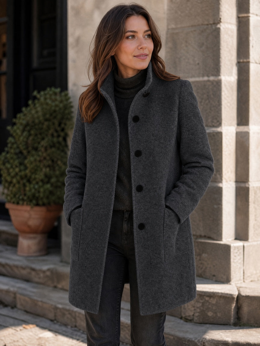 Three-quarter street style portrait of a model wearing the women's wool coat in dark charcoal gray with black front buttons.