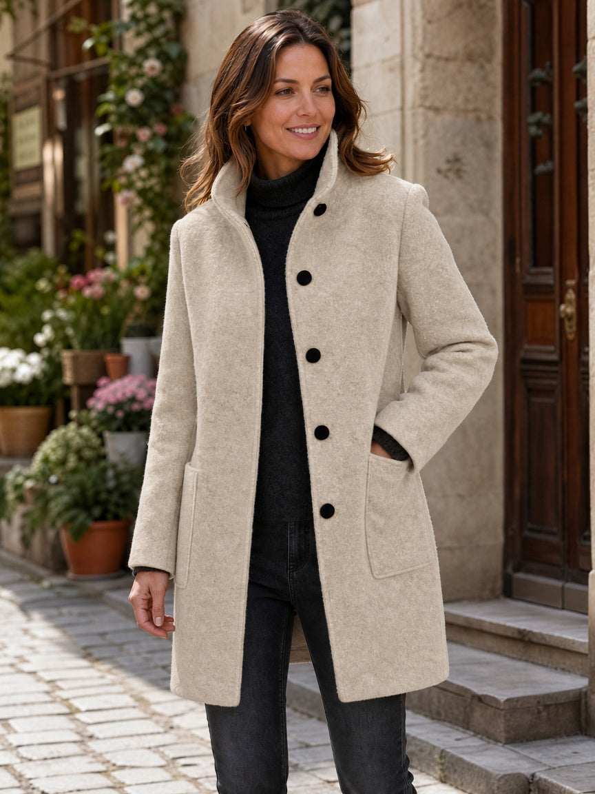 Three-quarter street view of a model wearing the dark charcoal gray wool-blend coat worn open over a dark top.
