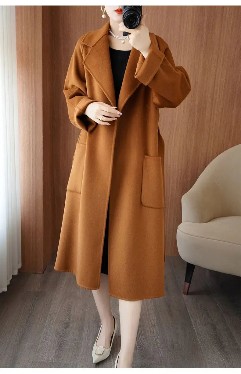 Full-length shot of a woman wearing a caramel brown longline wool-blend overcoat left open, paired with light-colored heels. 
