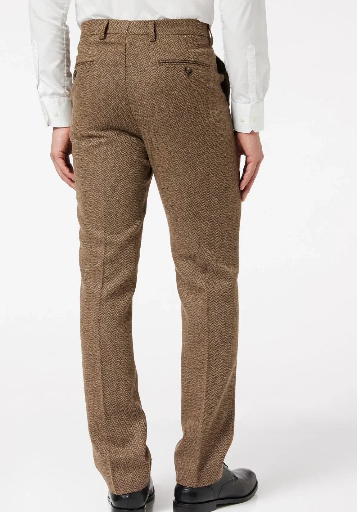 Full-length rear view of a man wearing brown wool herringbone flat-front dress pants with welt back pockets, a white dress shirt, and black shoes against a plain light background.
